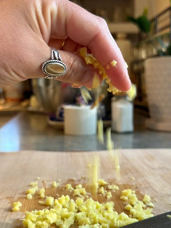Chopped fresh ginger sprinkled onto cutting board.