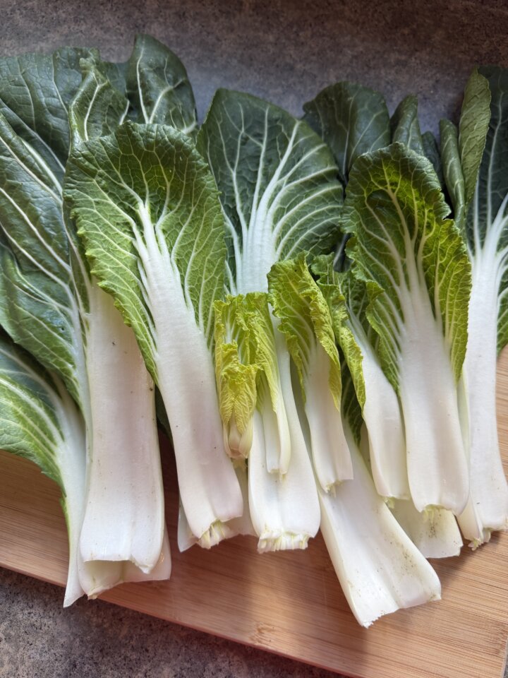 Fresh bok choy on wood cutting board.