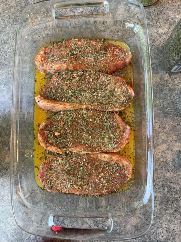 Pork tenderloin marinating in a glass pyrex dish on the counter.